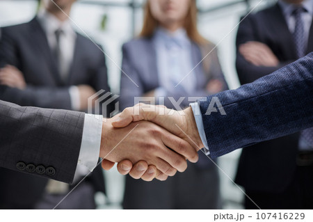 Business colleagues shaking hands in an office hallway Business colleagues shaking hands in an office hallway 107416229