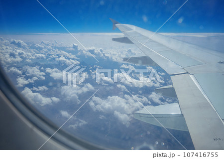 View from airplane window. Airplane wing against background of clouds in sky. View from passenger View from airplane window. Airplane wing against background of clouds in sky. View from passenger 107416755