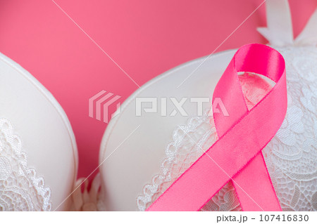Breast Cancer Awareness Month. Women's bra and pink ribbon on bright background. Health care concept, oncology diagnostics. 107416830