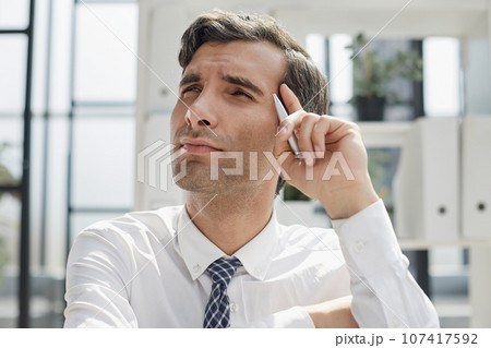 Image of successful businessman 30s thinking and holding index finger at forehead 107417592