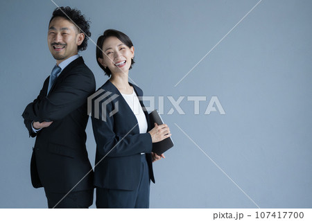 背中合わせのビジネスマンとビジネスウーマン　カメラ目線 107417700