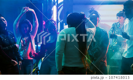 African american person having fun, dancing in the club at social gathering with funky people. Cheerful group of friends listening to music, enjoying party on the dance floor. Tripod shot. 107418013
