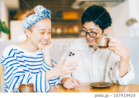 一緒にスマホを見る若い夫婦（カップル） 107419420