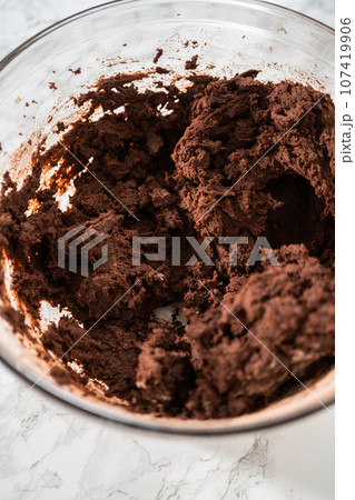Mixing ingredients in a large glass mixing bowl to bake peppermint white chocolate cookies. 107419906