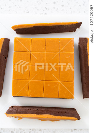Cutting caramel fudge into square pieces on a white cutting board. Cutting caramel fudge into square pieces on a white cutting board. 107420067