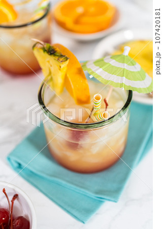 Freshly made Sunset cocktail garnished with a slice of fresh orange and pineapple. 107420181