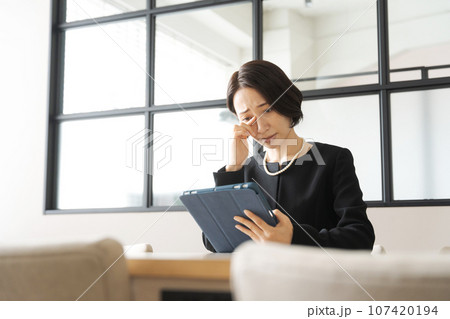 タブレット端末を見る喪服の女性 107420194