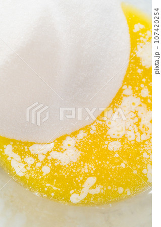 Mixing wet ingredients in a large glass mixing bowl to bake lemon blueberry bundt cake. 107420254