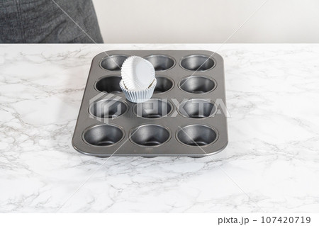Lining baking cupcake pan with foil liners to bake lemon cupcakes. 107420719