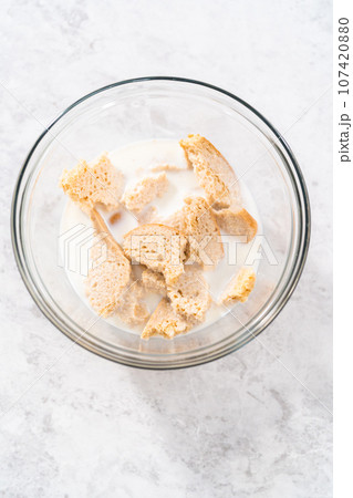 Soaking stale bread in milk to make meatloaf. 107420880