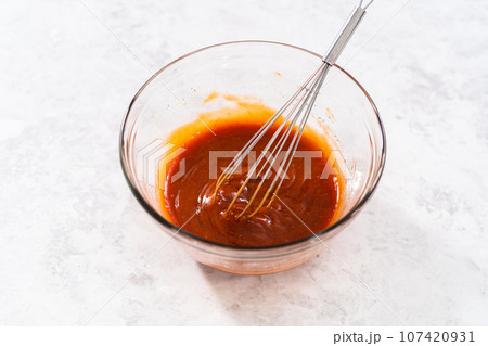 Mixing ingredients with a hand whisk to make a sweet glaze for meatloaf. 107420931