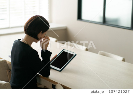 タブレット端末を見る喪服の女性 107421027