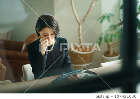 タブレット端末を見る喪服の女性 タブレット端末を見る喪服の女性 107421030
