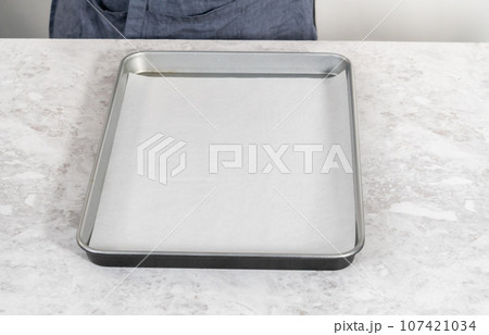 Spreading bread crumbs on a baking sheet lined with parchment paper to prepare dried bread crumbs. Spreading bread crumbs on a baking sheet lined with parchment paper to prepare dried bread crumbs. 107421034
