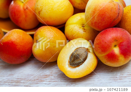 Whole and half fresh apricots on wooden table 107421189