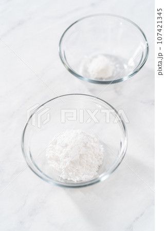 Measured ingredients in glass mixing bowls to prepare powdered sugar dusting. Measured ingredients in glass mixing bowls to prepare powdered sugar dusting. 107421345