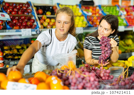 Teenage girl and her mother buying grape at grocery 107421411