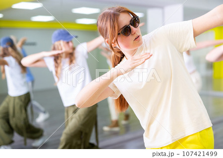 Young girl in sunglasses training breakdance Toprock moves in dance hall 107421499