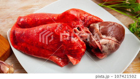 Wooden cutting board with raw lamb lungs and liver Wooden cutting board with raw lamb lungs and liver 107421502