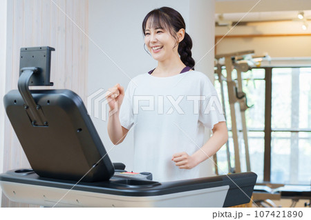 ランニングマシンを使ってトレーニングをする女性 107421890