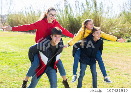 Happy teenage boys piggybacking girls 107421919