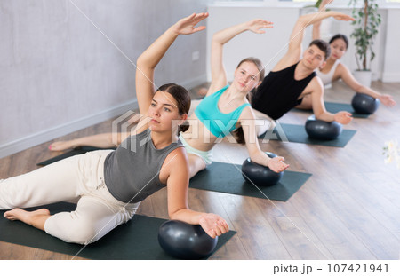 Group of people doing soft ball pilates exercises during group pilates class in fitness studio 107421941