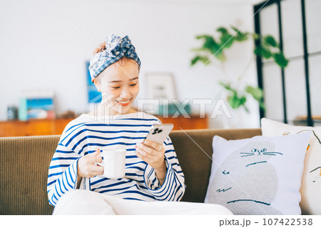 ソファに座ってスマホを使う女性 ソファに座ってスマホを使う女性 107422538