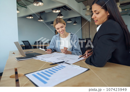 Two colleagues discussing project before showing presentation to team leader in office Two colleagues discussing project before showing presentation to team leader in office 107423949