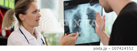 Family doctor shows x-ray picture to patient at appointment Family doctor shows x-ray picture to patient at appointment 107424552