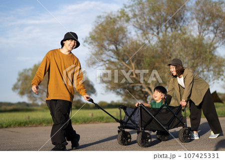 キャンプ・アウトドアカートに子供を乗せて引く家族イメージ 107425331