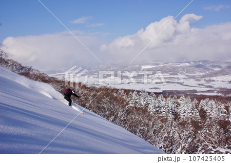青空と冬の羊蹄山　羊蹄山を滑るスキーヤー 107425405