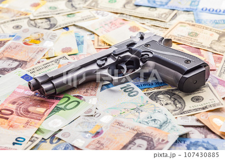 Handgun on various banknotes background. 107430885