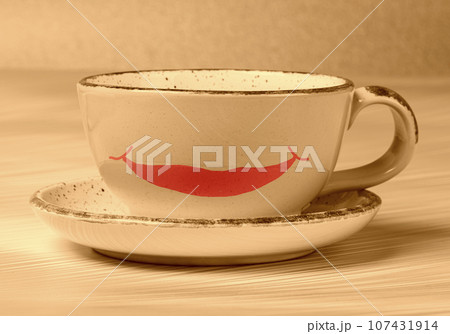 Ceramic cup with a painted smile in beige toning. Morning coffee or tea with a good mood. Ceramic cup with a painted smile in beige toning. Morning coffee or tea with a good mood. 107431914