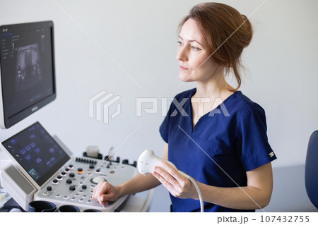 Doctor woman doing ultrasound scanning diagnostic of thyroid gland sitting in office in clinic. 107432755