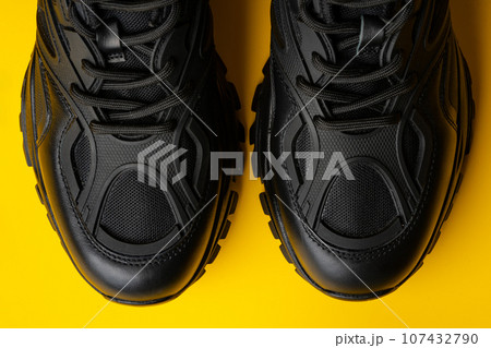 Black new sport sneakers on yellow background Black new sport sneakers on yellow background 107432790