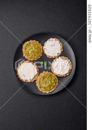 Round snacks with crispy chips or crackers with cream cheese and pesto 107433929