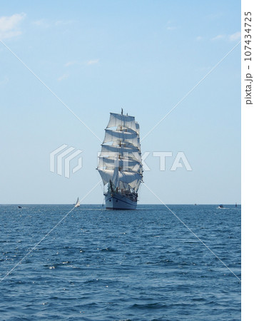 A sailing ship with white sails on three masts at sea. The concept of a cruise, vacation at sea, sailing, yachting. A sailing ship with white sails on three masts at sea. The concept of a cruise, vacation at sea, sailing, yachting. 107434725