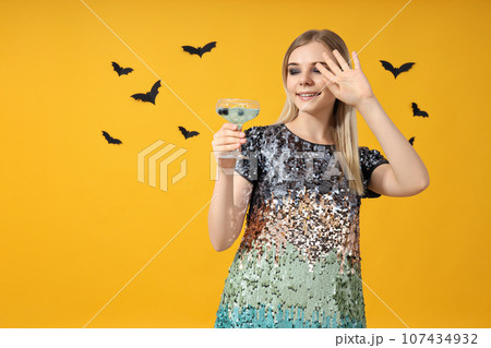 A girl at a party in the style of Halloween with a cocktail in her hands A girl at a party in the style of Halloween with a cocktail in her hands 107434932