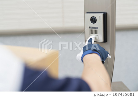 家のインターホンを押す40代配達員 107435081