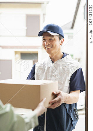 荷物を渡す40代配達員 107435159