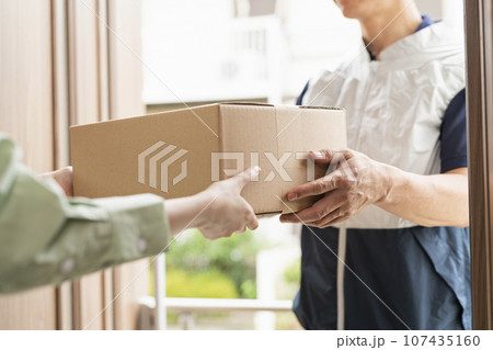 荷物を渡す40代配達員 107435160