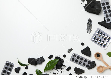 Activated charcoal tablets with wooden spoon and leaves Activated charcoal tablets with wooden spoon and leaves 107435427