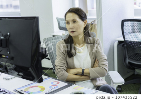 オフィスでデスクワークをするシニア女性 オフィスでデスクワークをするシニア女性 107435522