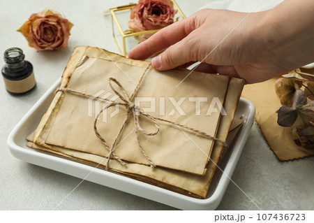Old letters in hand, white plate, ink bottle and roses on light background 107436723