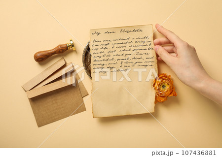 Vintage letter with text, hand, envelopes, rose and stamp on beige background, top view 107436881