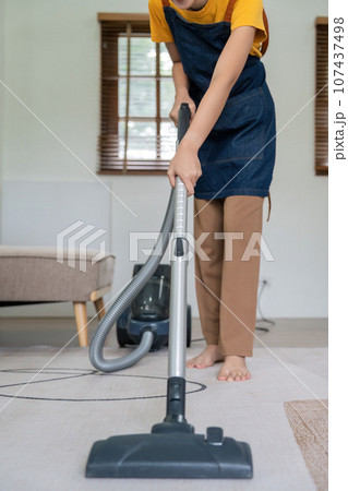 Asian woman cleaning in living room at home. Housekeeper or maid cleaner feel happy use vacuum cleaner to clean 107437498