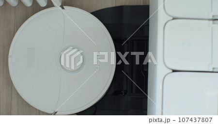 Robot vacuum cleaner started cleaning in a living room on floor from charging station. Smart cleaning technology. 107437807