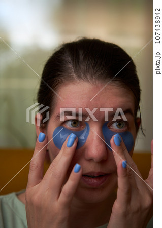 Woman is using cosmetic patches on face. 107438942