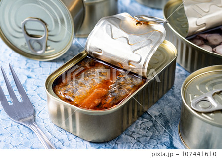 Various canned food in metal cans on blue background 107441610