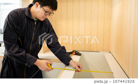 Asian male furniture assembler using tape measure Asian male furniture assembler using tape measure 107441928